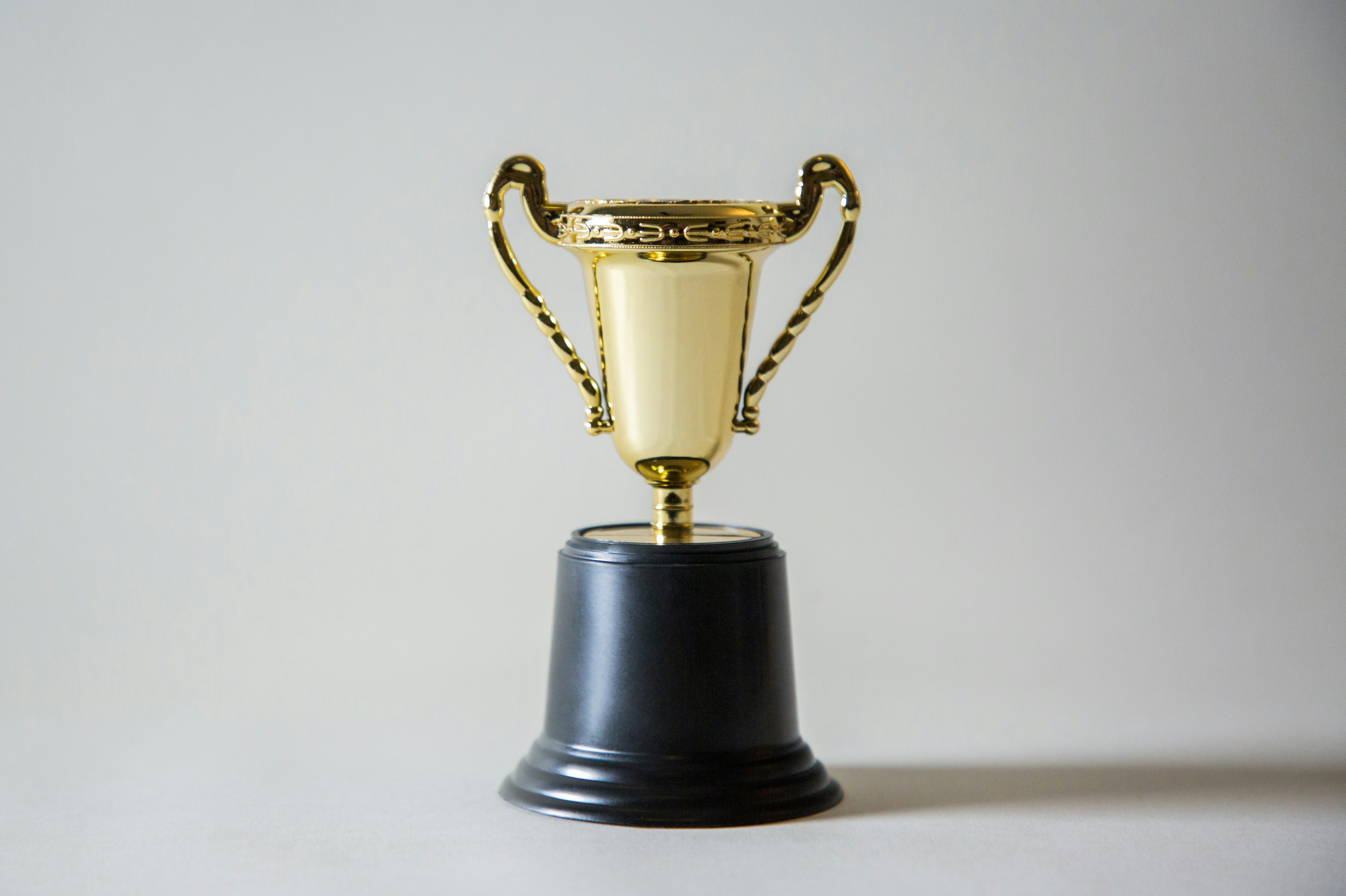 A small gold award cup sits in front of a white background